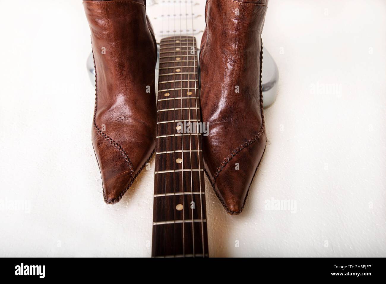 Silver electric guitar and brown women's high heels boots Stock Photo Alamy