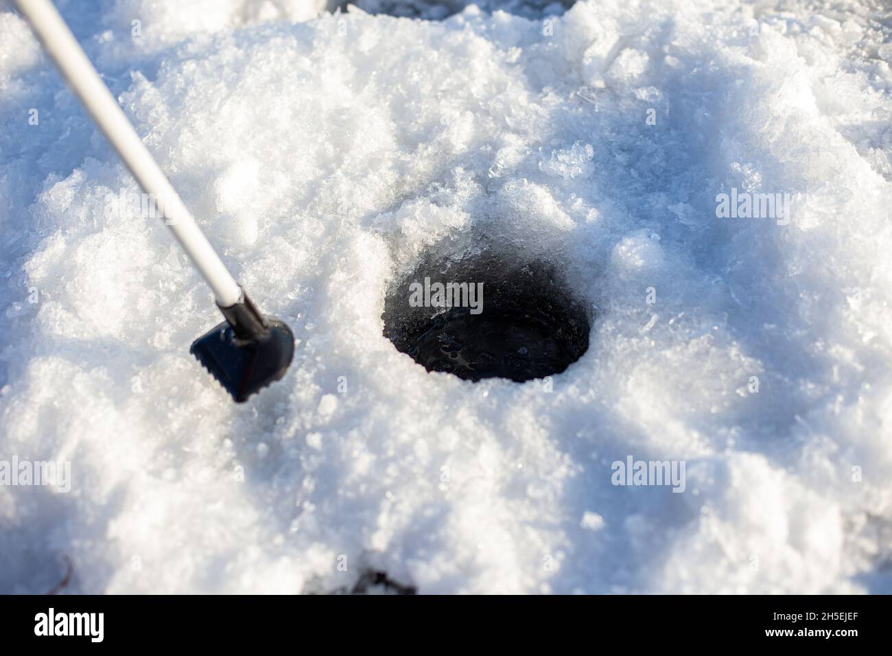 Hole in ice. Round hole cut through ice of frozen water for fishing in winter Stock Photo