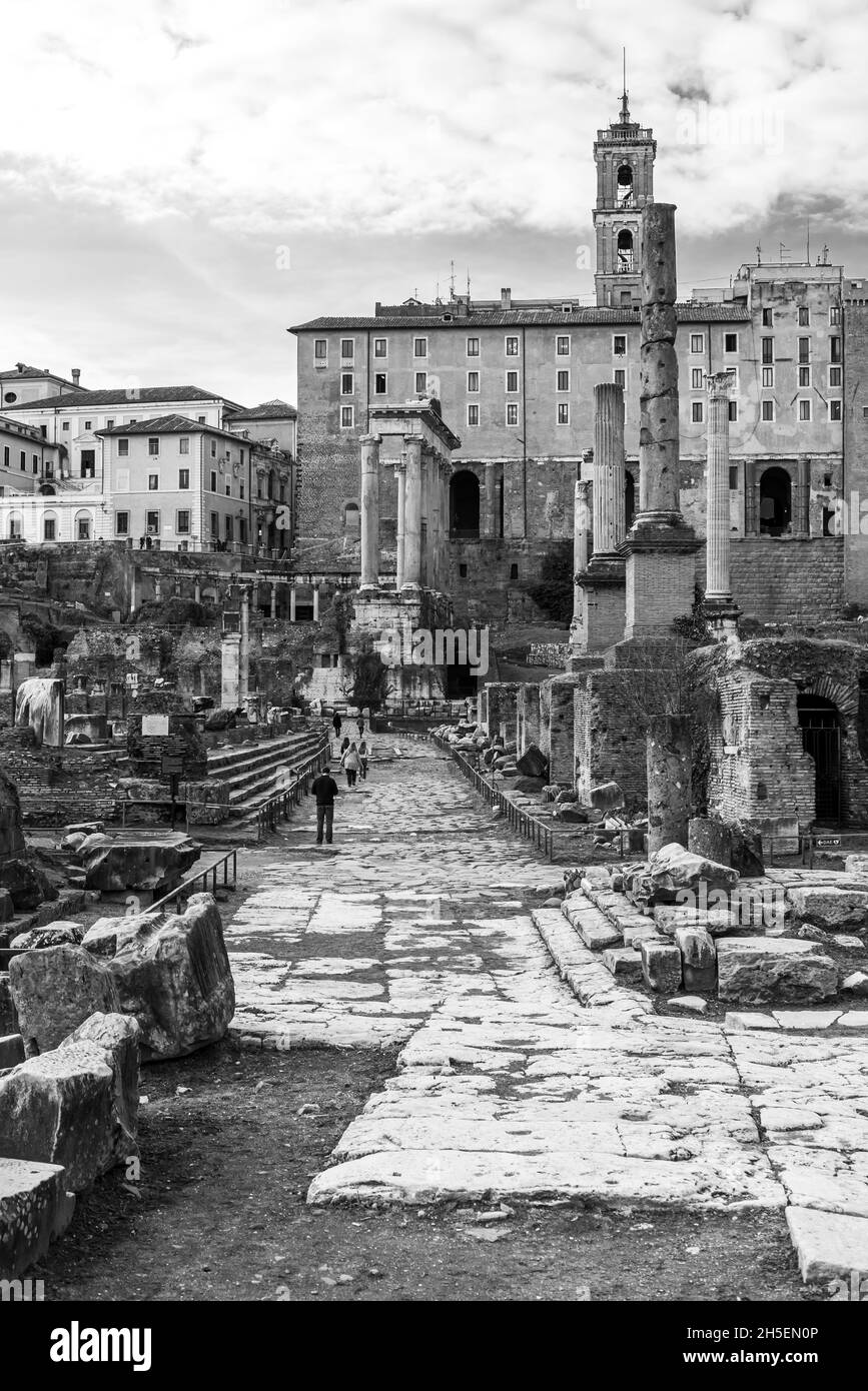 Black and white photo of italian landscape showing ruins of roman forum in front of a medieval church Stock Photo