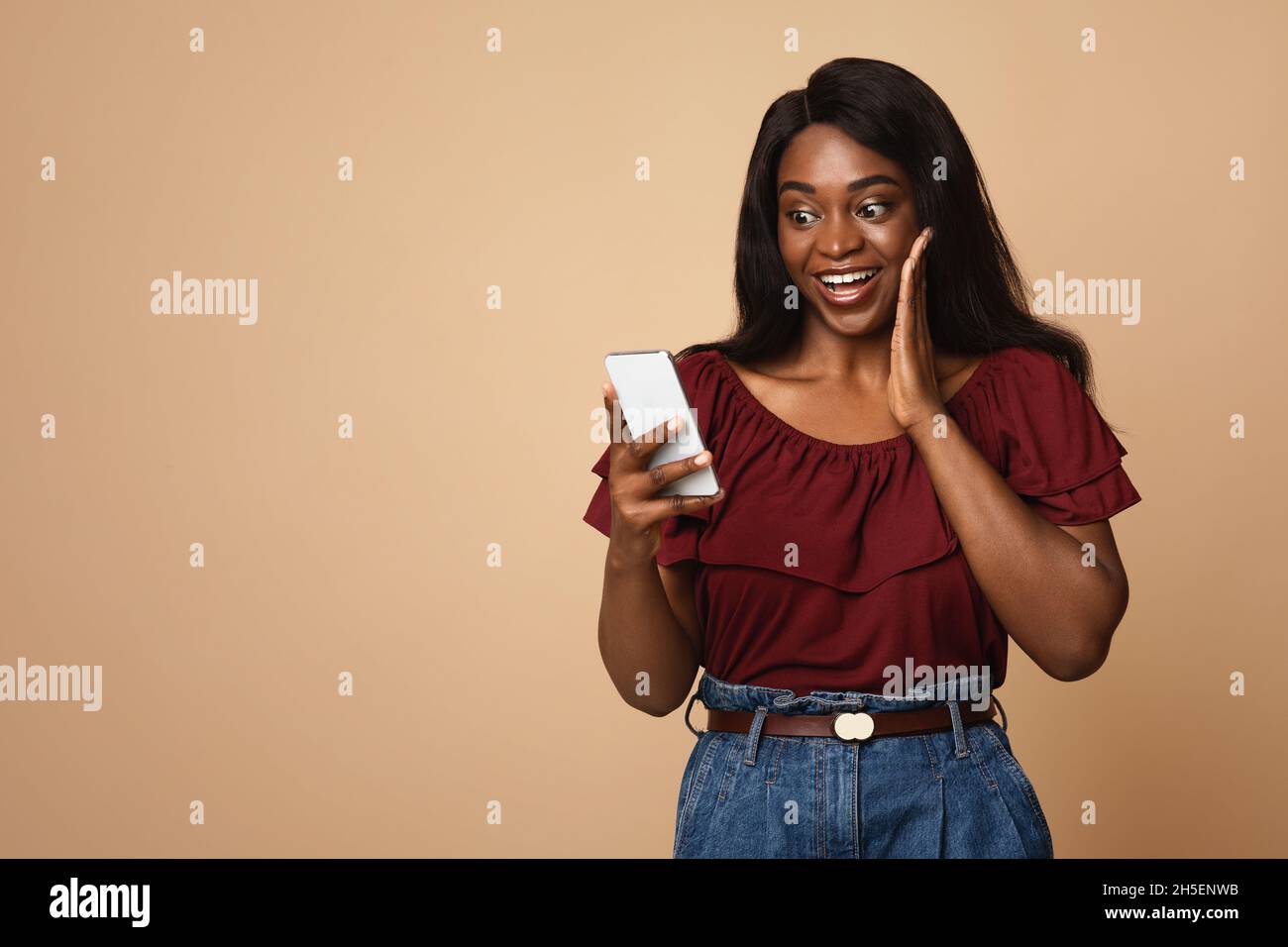 Emotional black woman using nice mobile app on smartphone Stock Photo