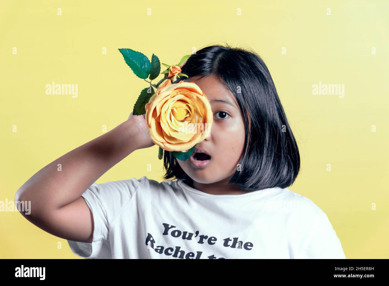 Indonesian girl holding yellow flower on yellow background Stock Photo