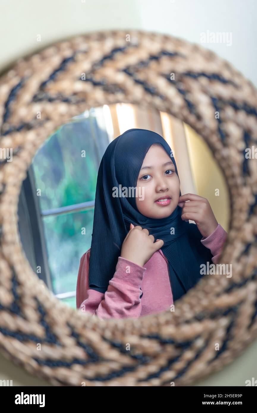 Girl wearing his hijab on mirror Stock Photo