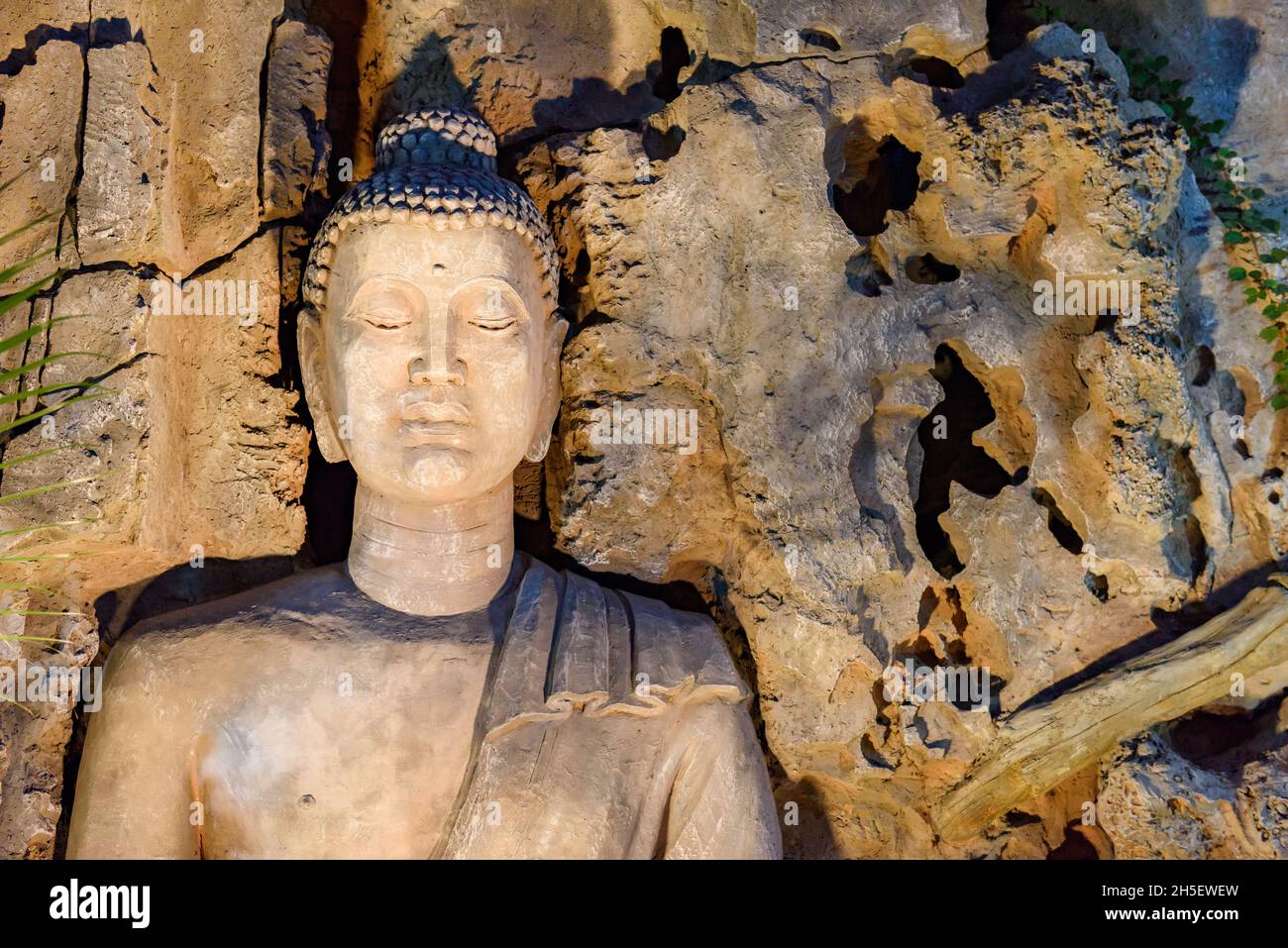 Closeup of stone Buddha statue carved into cave wall. Stock Photo