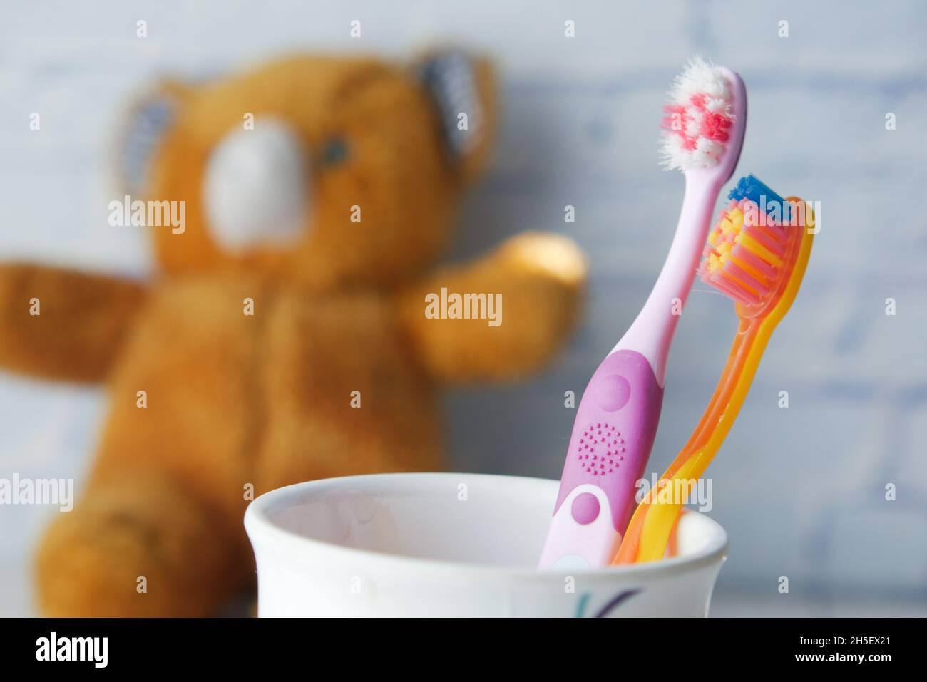 colorful child toothbrushes in white mug against a wall Stock Photo - Alamy