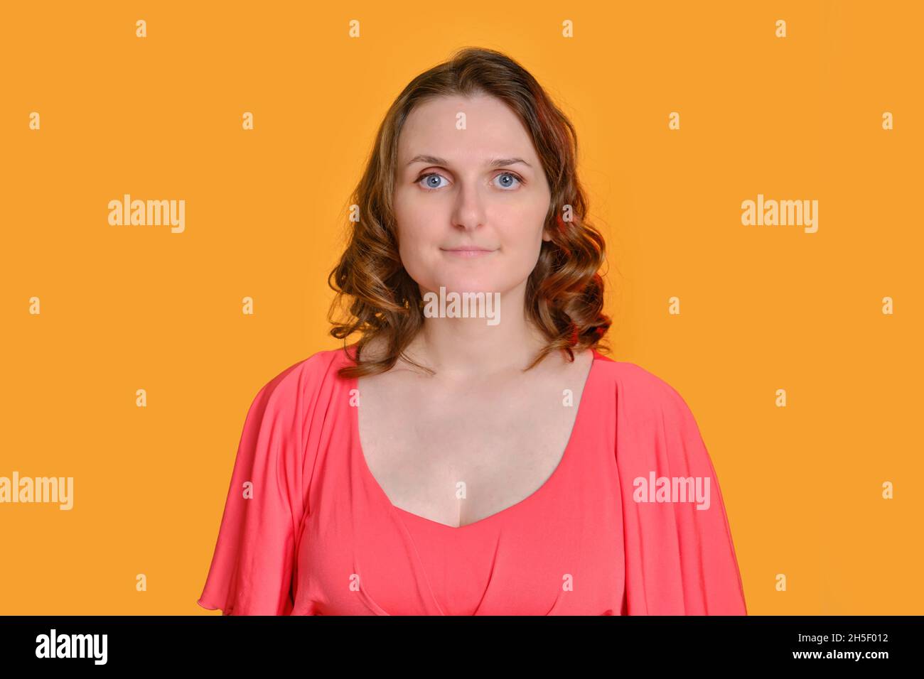 Portrait of a smiling woman in a red dress on a yellow studio ...