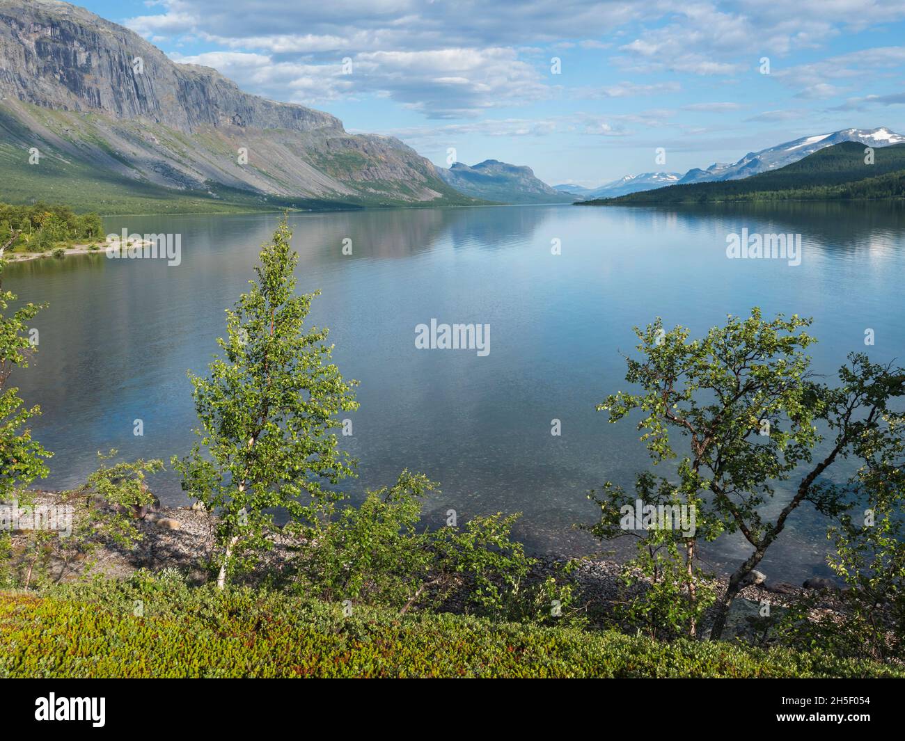 Beautiful moring on the shore of lake Lulealven, Lule river dam in Saltoluokta in Sweden Lapland. Reflection of mountains, tree and sky with dramatic Stock Photo