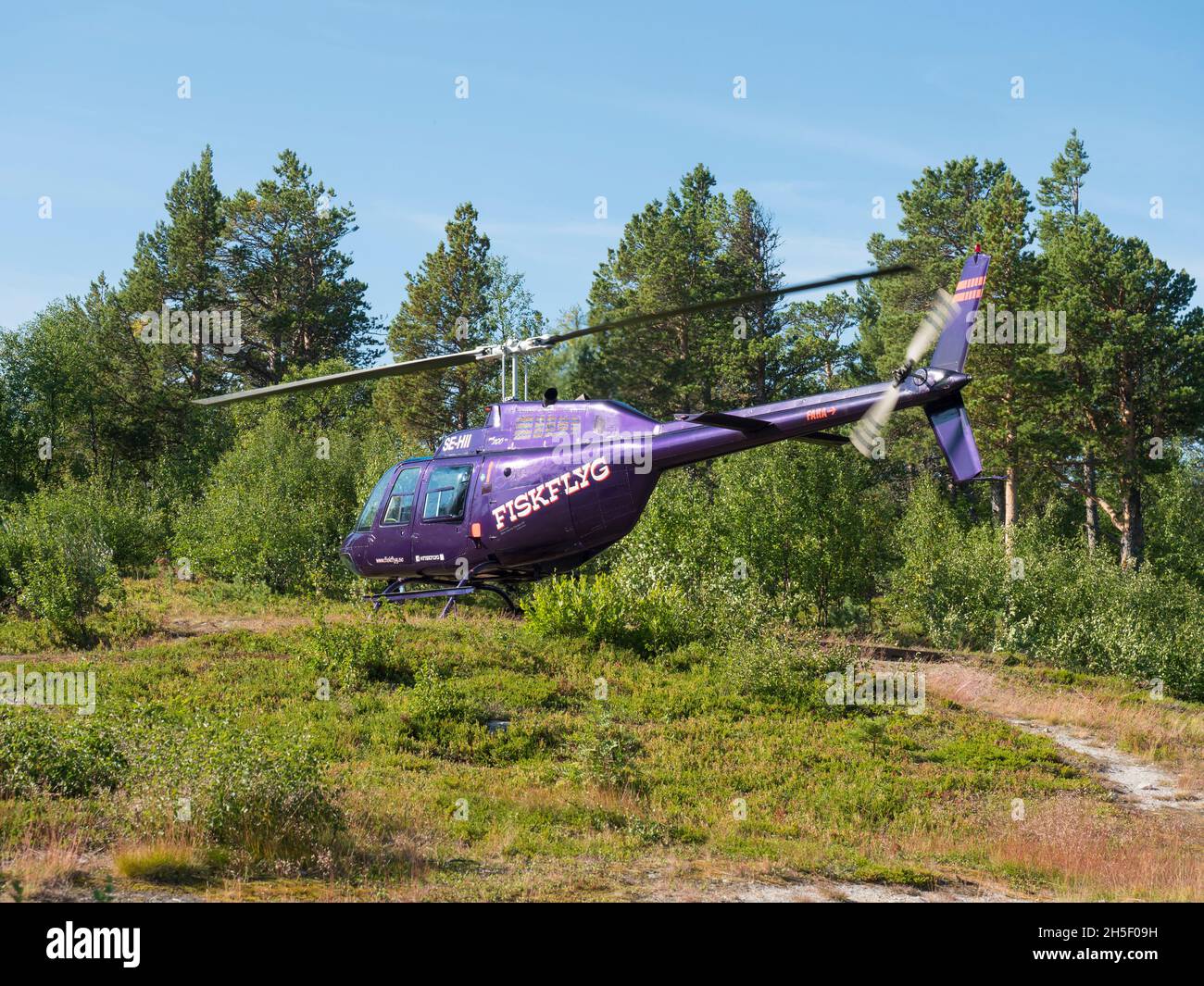 Jokkmokk, Norrbotten, Sweden, Agust 7, 2021: violet helicopter of Fiskflyg lands with supplies for Saltoluokta Fjallstation STF mountain lodge on Stock Photo