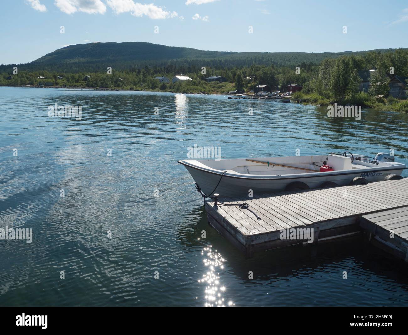 Saltoluokta, Norrbotten, Sweden, Agust 7, 2021: motor boat fasten at wooden pier in Saltoluokta saami village at Lule river, Lulealven lake with Stock Photo