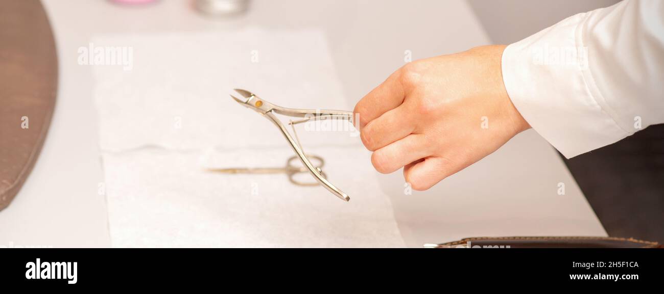 Nail nippers in the hand of female manicure master putting to the towel
