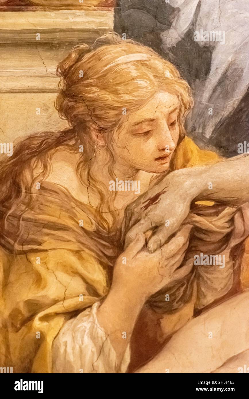 Detail of medieval painting showing a sad Mary Magdalene kneeling before the dead body of Jesus while holding his hand Stock Photo