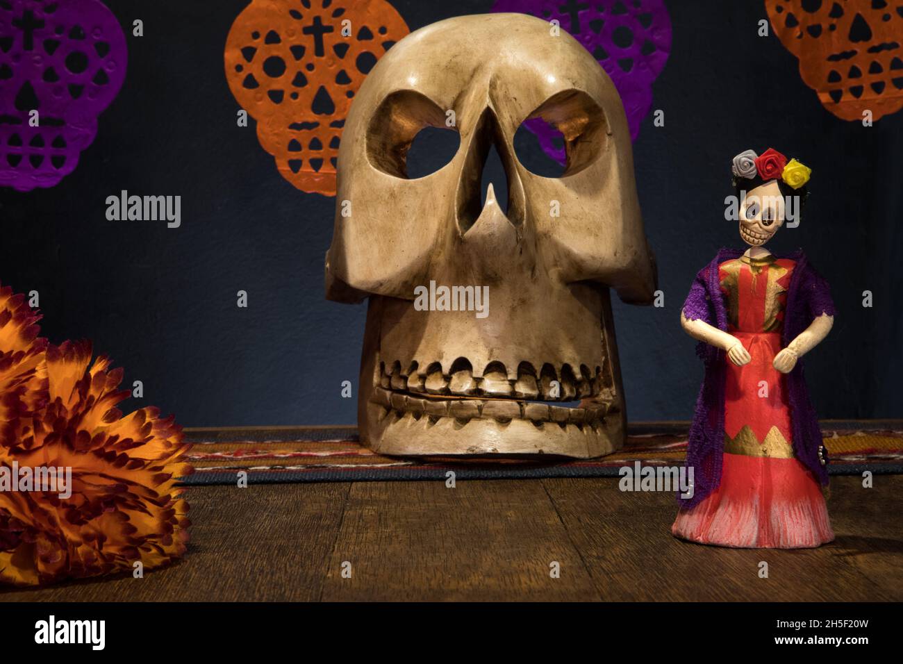 Closeup shot of a handcrafted skull mask and a Catrina figurine on a table on a Day of the Dead Stock Photo