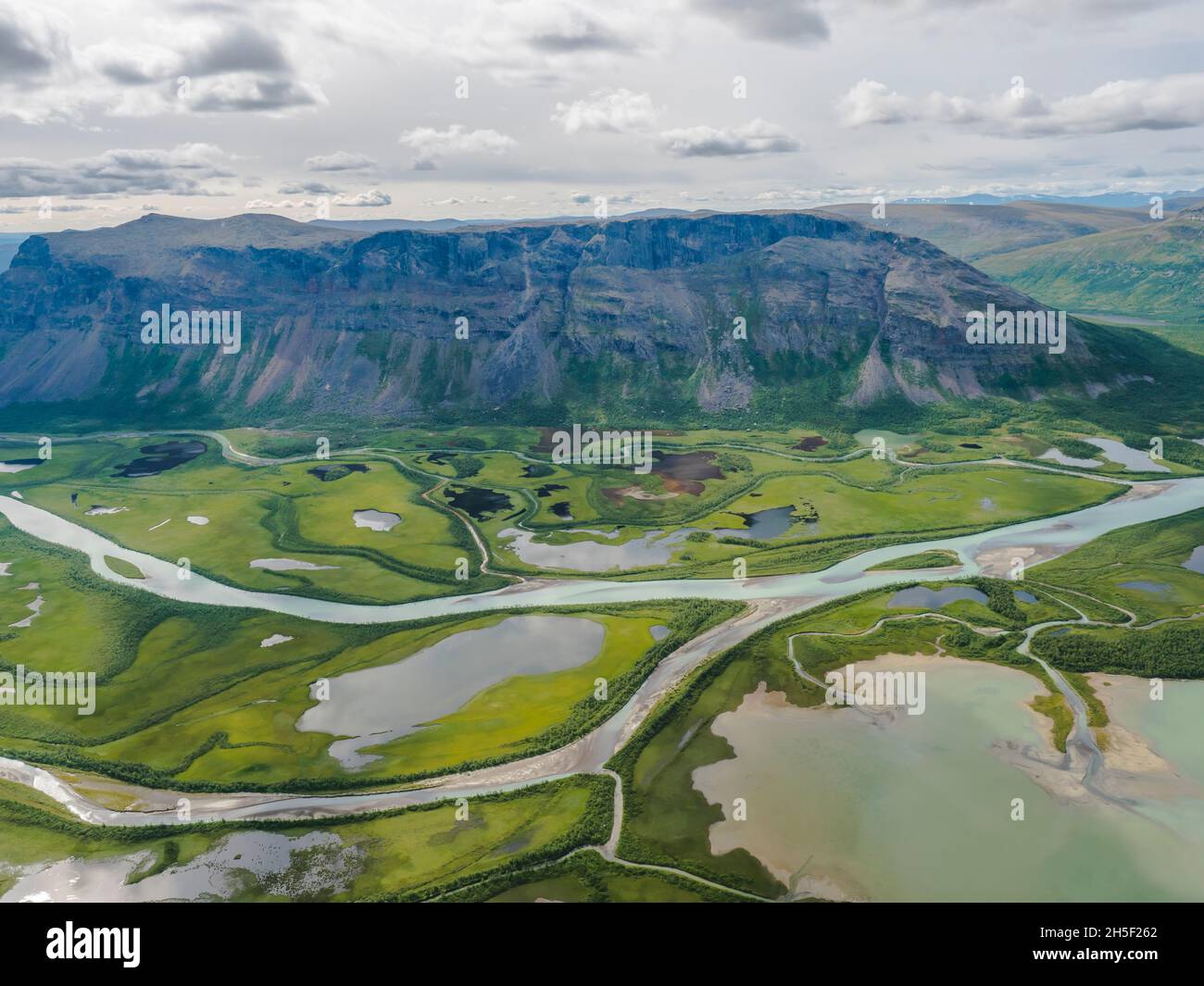 Aerial scenic view from Skierffe rock summit on glacial Rapadalen river delta valley at Sarek national park with meanders, lakes, mountains and birch Stock Photo