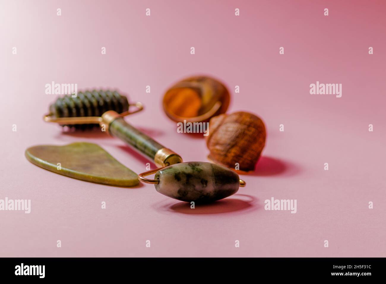 Jade scruber massager and roller facial massager on a pink background. Stock Photo