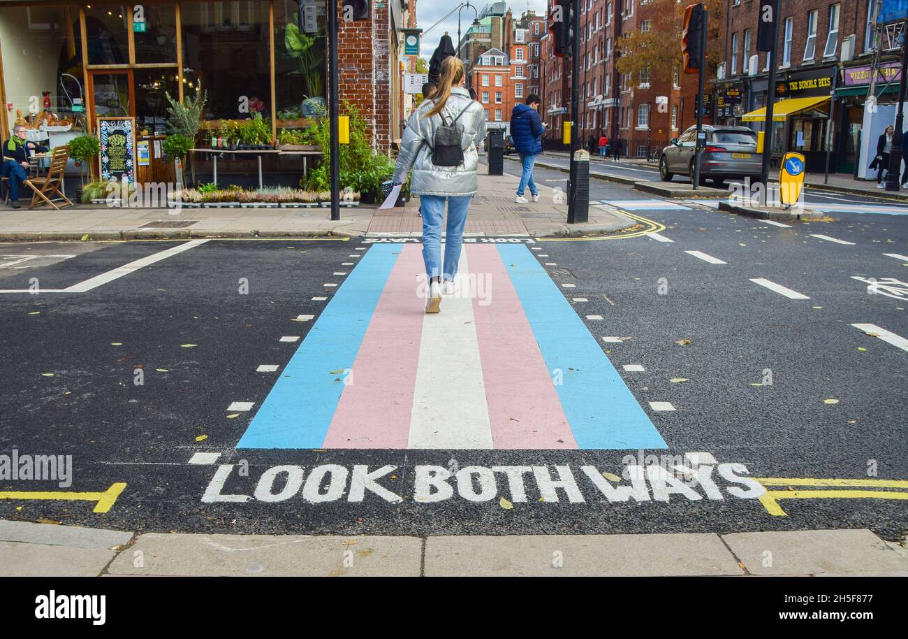 A woman walks along a pedestrian crossing with trans flag colours in Bloomsbury.Four new crossings with trans flag colours have been unveiled on Marchmont Street and Tavistock Place, in support of the trans community. Stock Photo