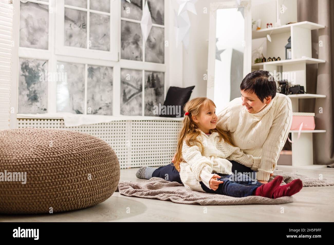 Mother and daughter unwrapping a present lying on the floor in the living room Stock Photo