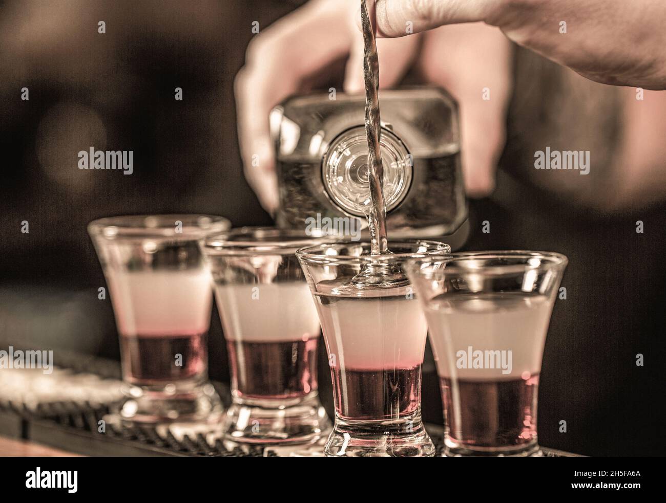 Shots at the nightclub. Red alcoholic drink in glasses on bar. Red cocktail at the nightclub. Barman preparing cocktail shooter Stock Photo