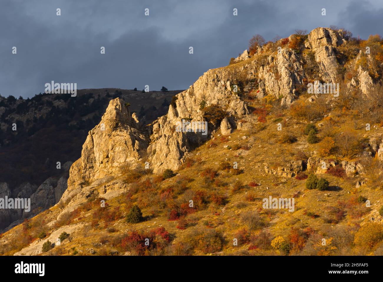 Autumn colorful landscape of the mountain. Unusual bizarre slopes of Mount Demerdzhi in the Crimea. Warm orange sunset light. Travel in autumn. Beauti Stock Photo