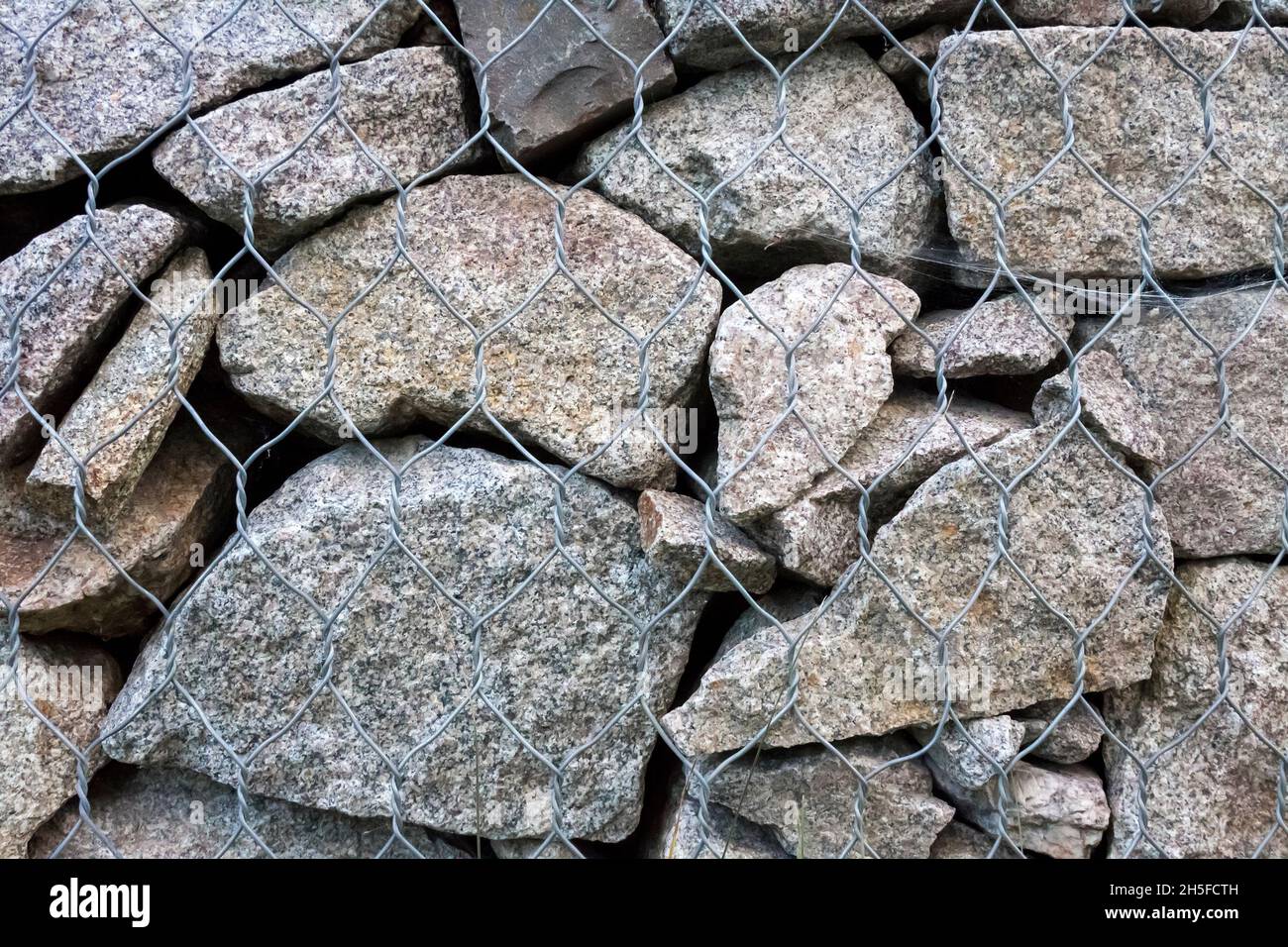 Gabion wall closeup. Textured background. Gabion is stones in wire mesh