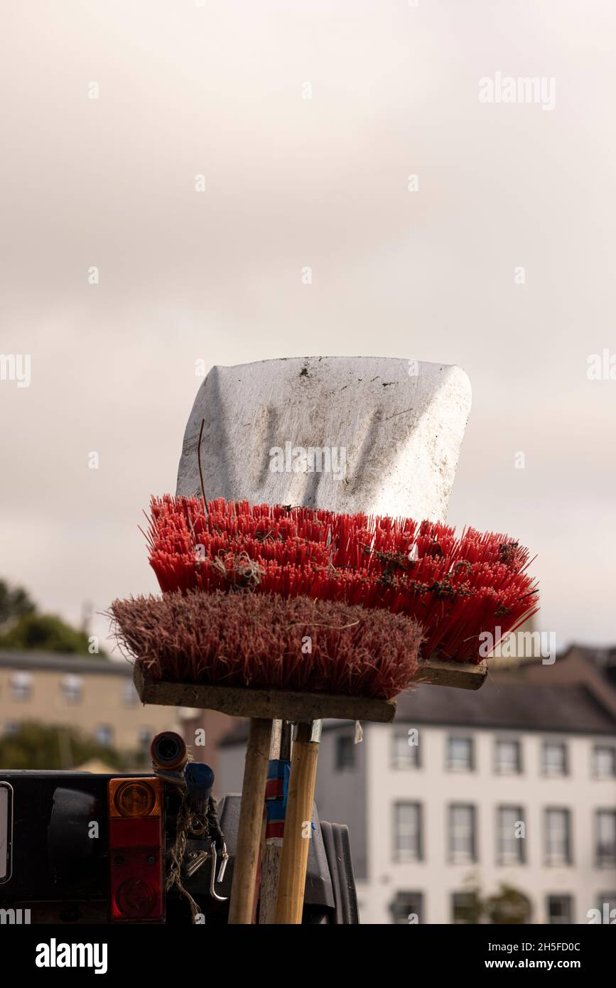 Sweeping brushes and shovel against the sky, stacked in the back of a