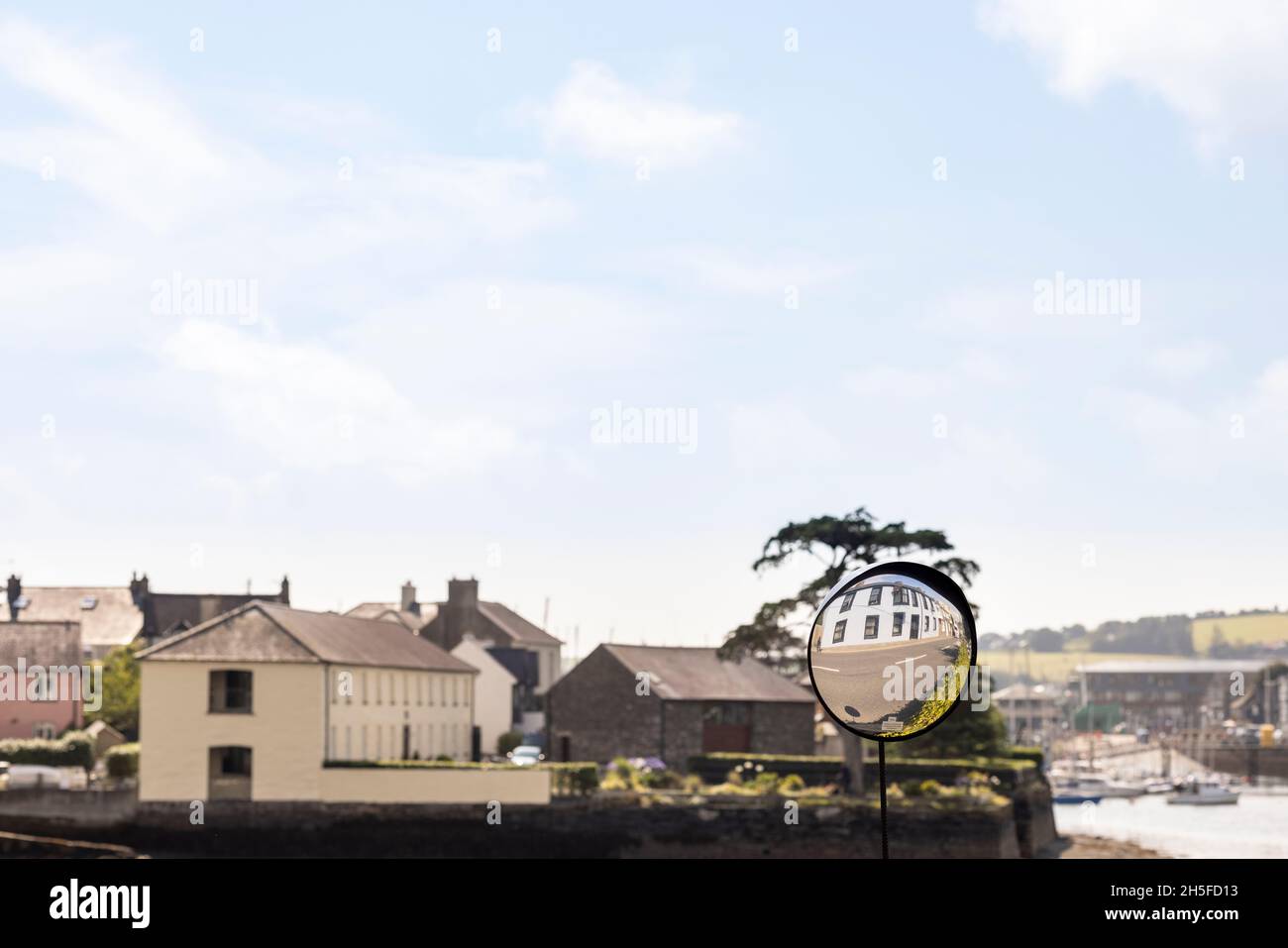 Convex mirror on the street to see oncoming traffic reflecting a building in Kinsale, County Cork, Ireland Stock Photo