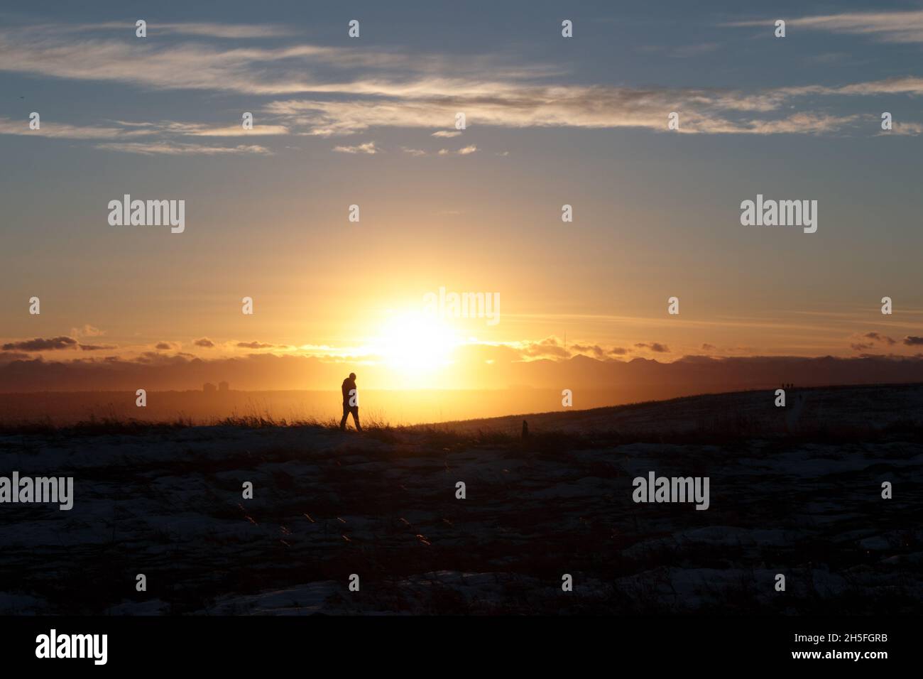 Silhouette of a person walking on a field at sunset Stock Photo - Alamy