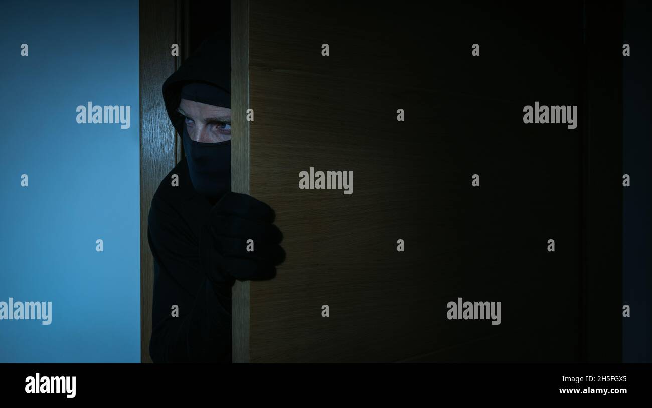 house robbery - burglar breaking into a house at night. home security and insurance concept Stock Photo
