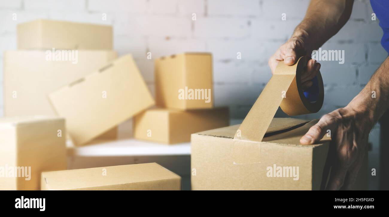 warehouse order picker packing and sealing cardboard box with tape for dispatch Stock Photo