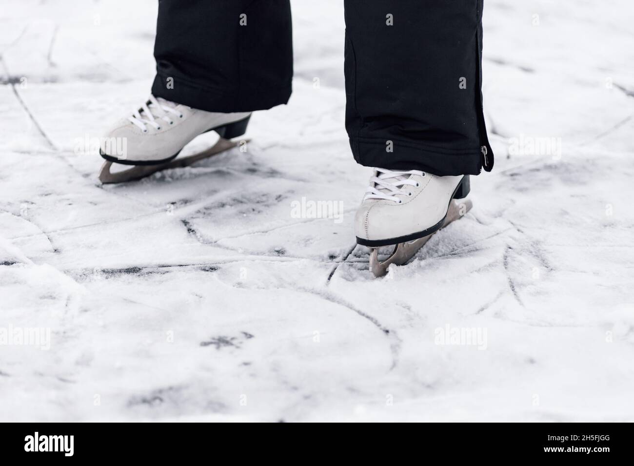 Figure skating skates. Close-up of man's feet standing on skates on ice of a frozen lake Stock Photo