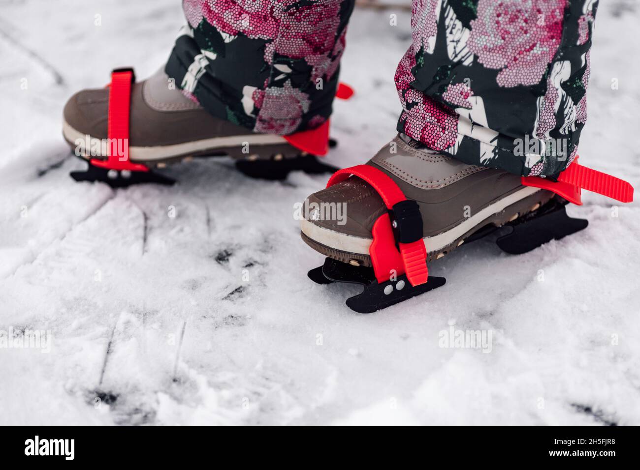 Close-up of children skates. Children feet in warm winter suit with children ice skates tied to their shoes, snowy winter Stock Photo
