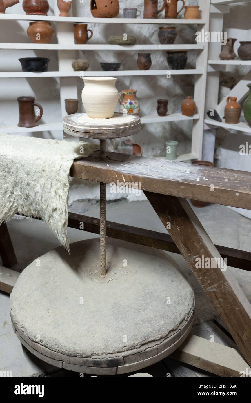 Pottery workshop studio, white clay pot stands on a pottery wheel, vertical photo Stock Photo
