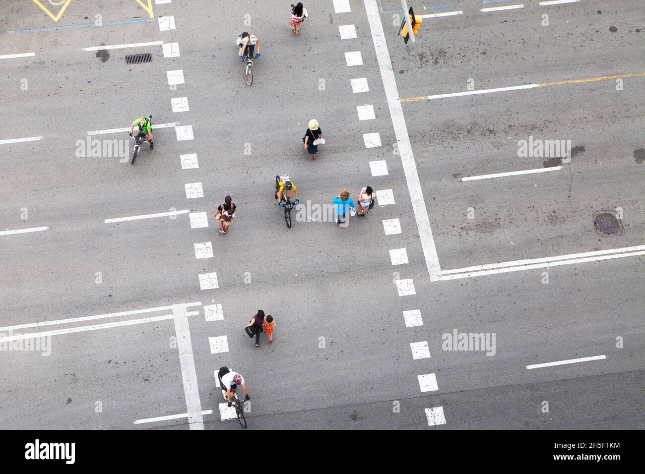 Fußgänger und Radfahrer (keine Erkennbarkeit) auf einer grauen Verkehrsstraße mit weißen gestrichelten Linien. Keine Autos.  Aus der Vogelperspektive. Stock Photo