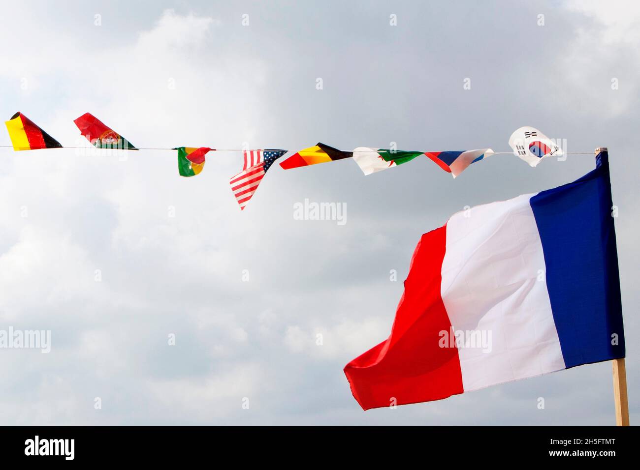 Französische Flagge im Vordergrund sowie weitere kleine Flaggen diverser Nationen wie USA, Deutschland, Südkorea, etc., Nizza, Frankreich. Stock Photo