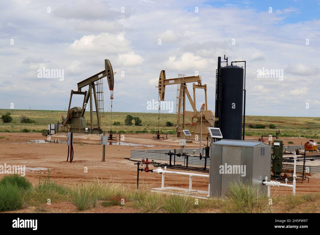 Two oil gas well pump jack at drilling site with equipment and
