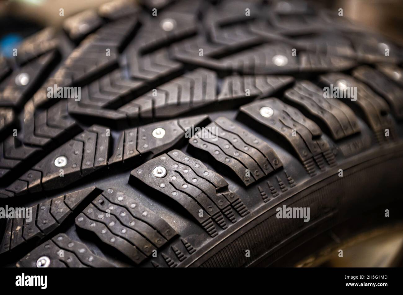 closeup of snow tire with metal studs, which improve traction on icy surfaces, studded winter tyre Stock Photo