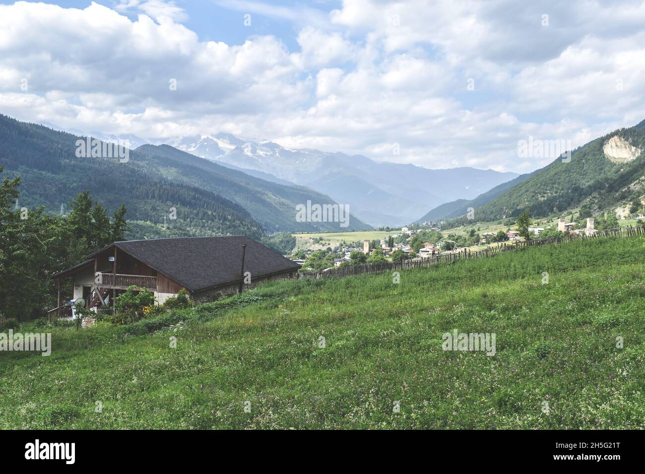 View of highland townlet Mestia in Svaneti region, Georgia. Green meadows, valles and rural houses. Caucasus mountain range, snow capped mountains in Stock Photo