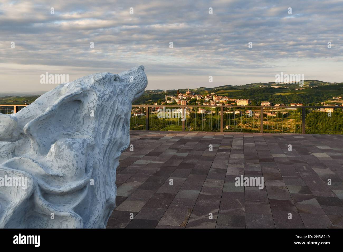 Statue representing a wolf on the panoramic terrace of Montelupo Albese with the Langhe hills and the town of Rodello in the background, Piedmont Stock Photo