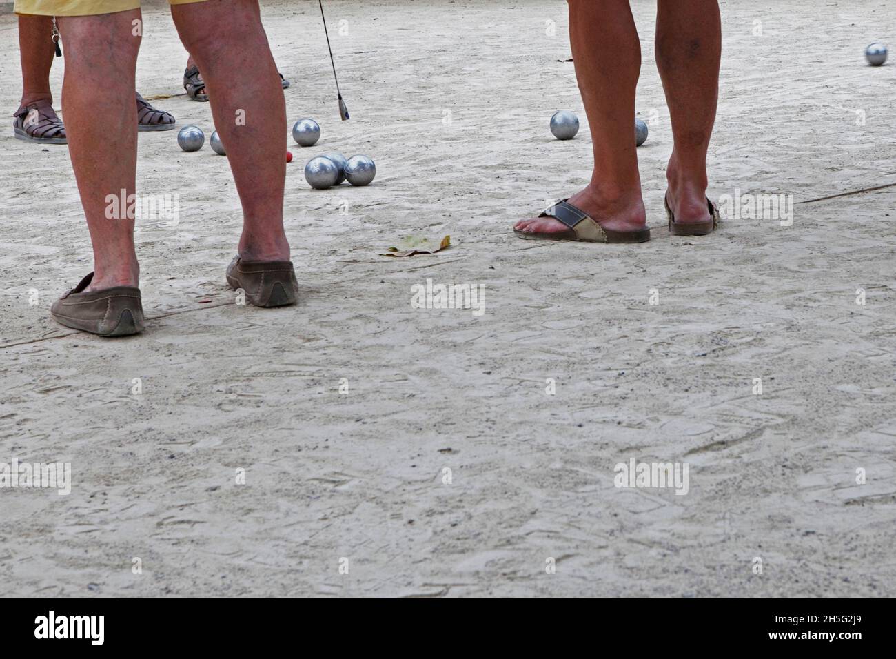 Franzosen, die gerade -auf einem öffentlichen Platz- Boule spielen. Keine Erkennbarkeit, da nur Beine. Cannes, Frankreich. Stock Photo