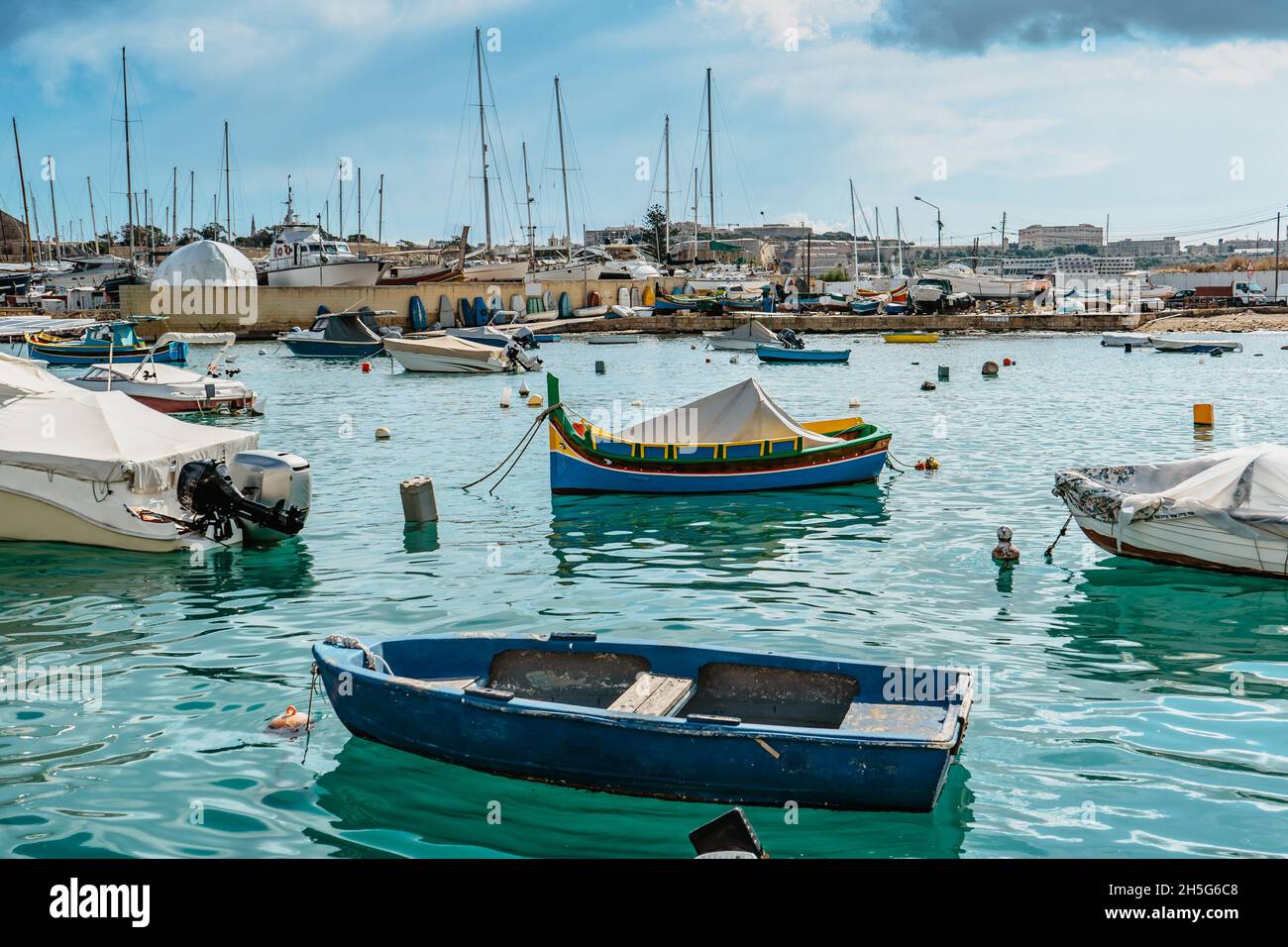 Traditional colorful Malta boats in Sliema harbor,yachts in background.Crystal clear turquoise water.Travel vacation concept.Blue-yellow fishing boat Stock Photo