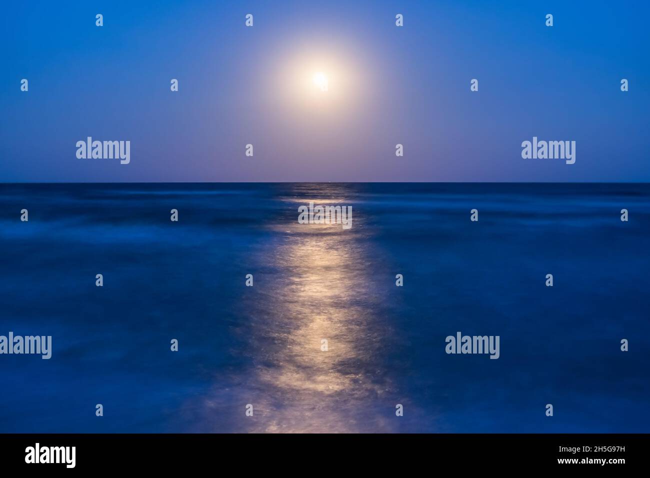 Night landscape with full moon and lunar path on sea, long exposure Stock Photo