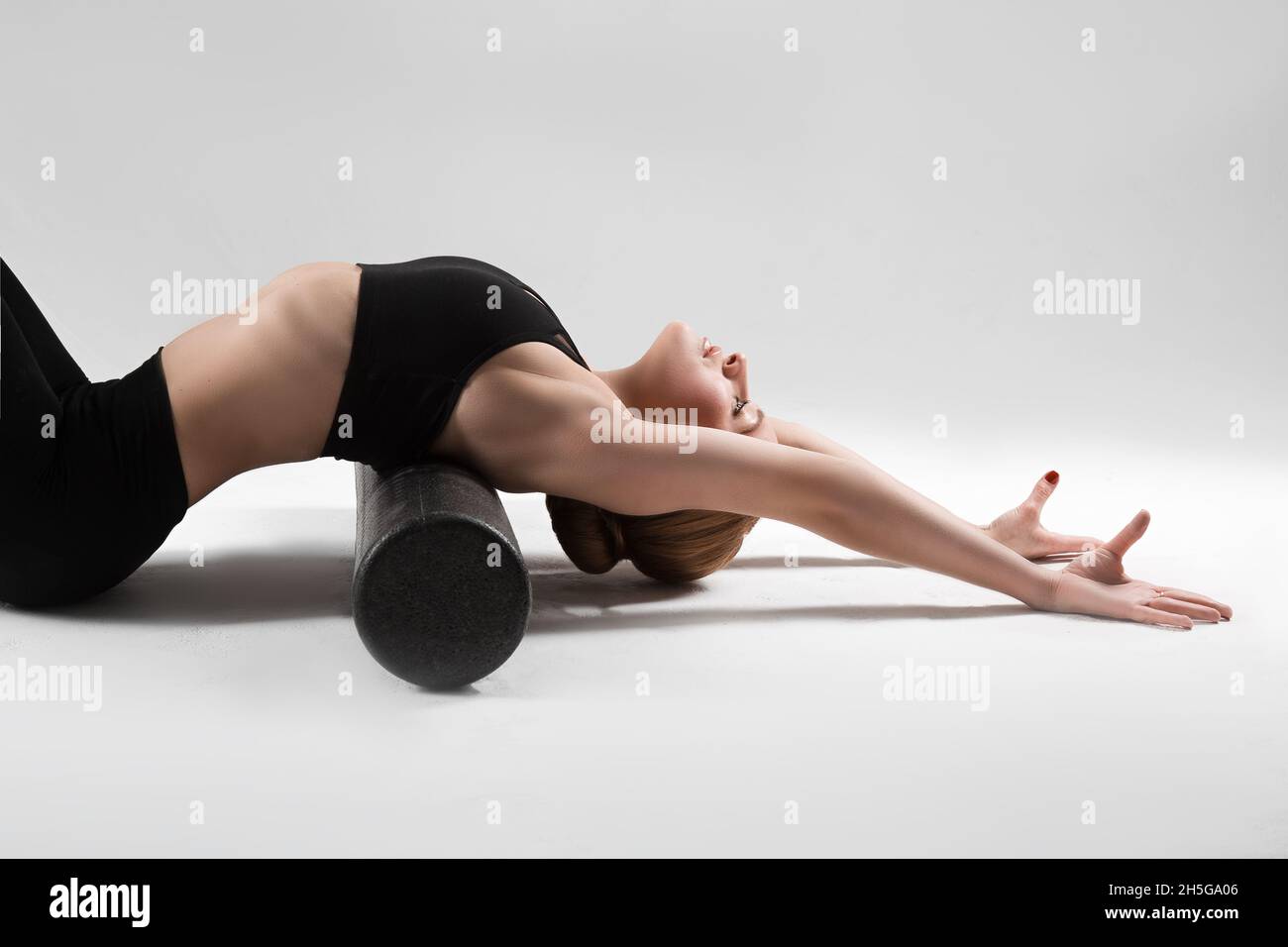 A professional yoga and pilates trainer shows exercises from yoga, pilates, stretching and other types of fitness on a mat with equipment, with fitnes Stock Photo