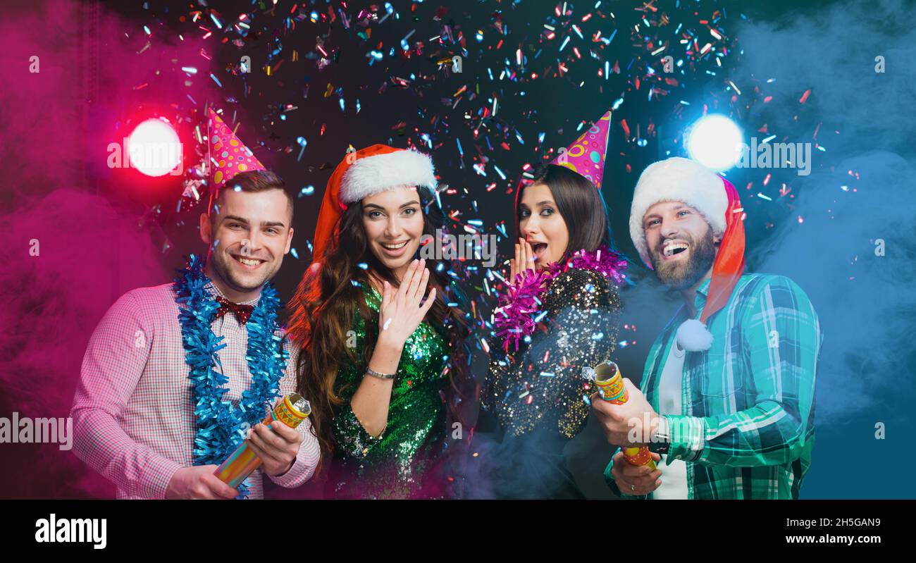 Party Poppers. New Year's party of best friends. A group of young people in New Year's and birthday hats Stock Photo