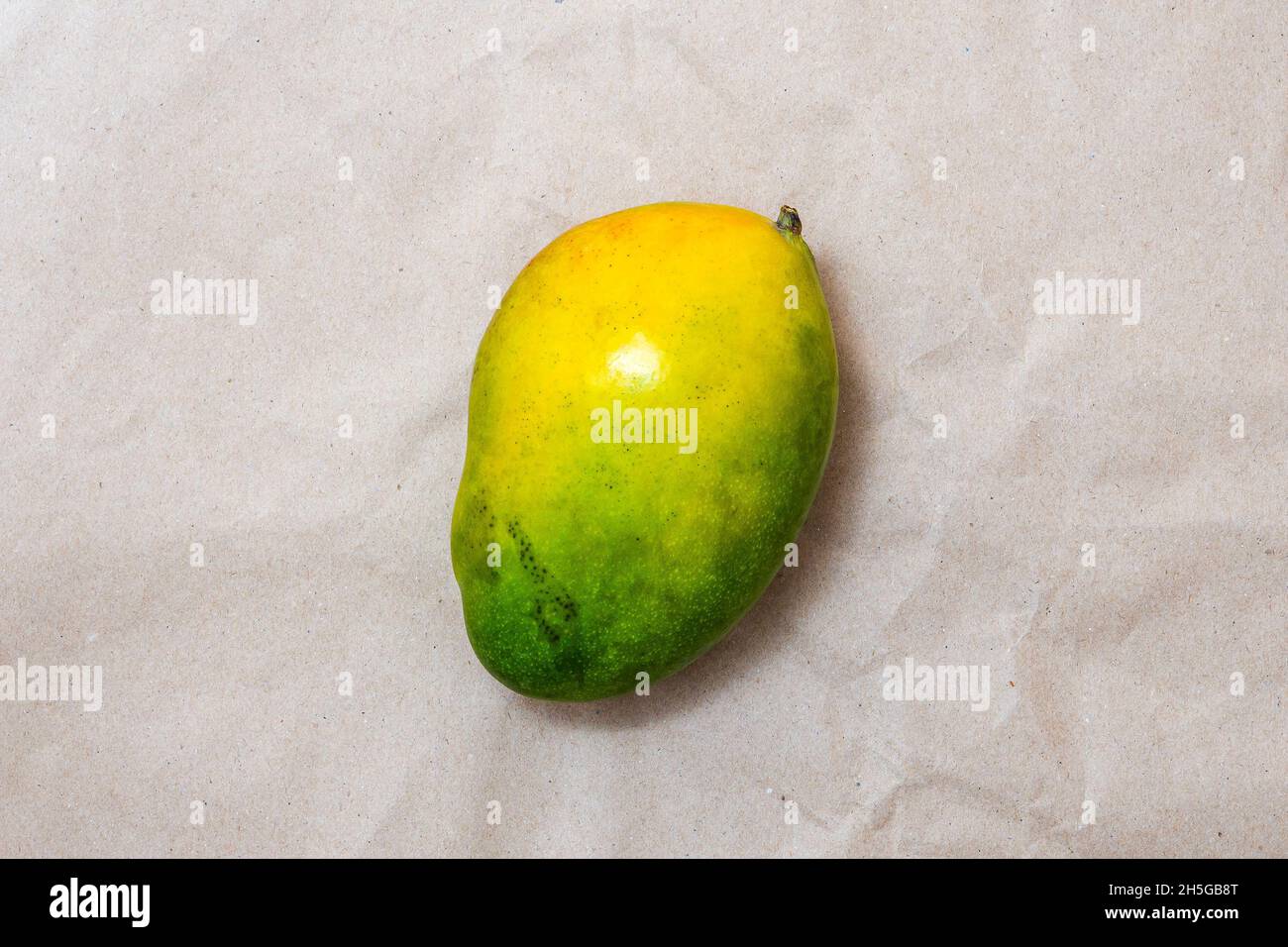 Ripe green and yellow mango fruit on brown craft paper. Top view. Stock Photo