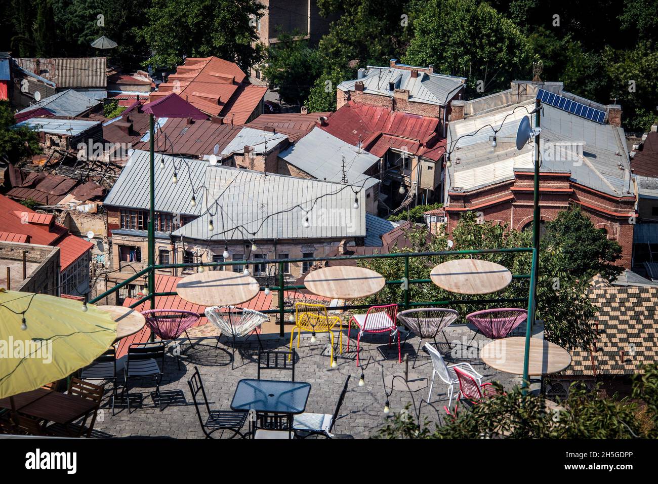 Looking down at boho patio cafe above roofs of funky old town Tbilisi Georgia with one building below caved in - selective focus Stock Photo