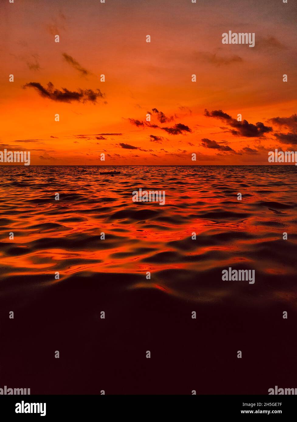 Vertical shot of a bright orange sunset sky over a sea with waves Stock ...