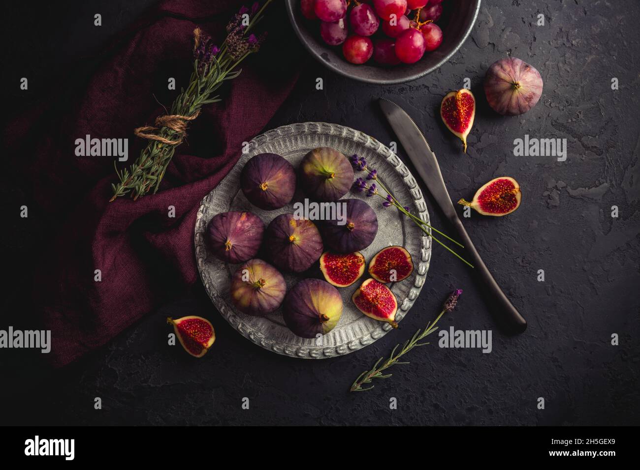 Organic fresh figs with red grapes and lavender on dark background Stock Photo