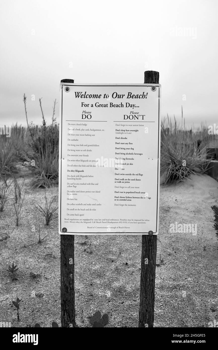 “Welcome to Our Beach” sign with the “Do and Don’t” list of activities on Long Beach Island, NJ, USA. Dune grass and other native plants growing Stock Photo