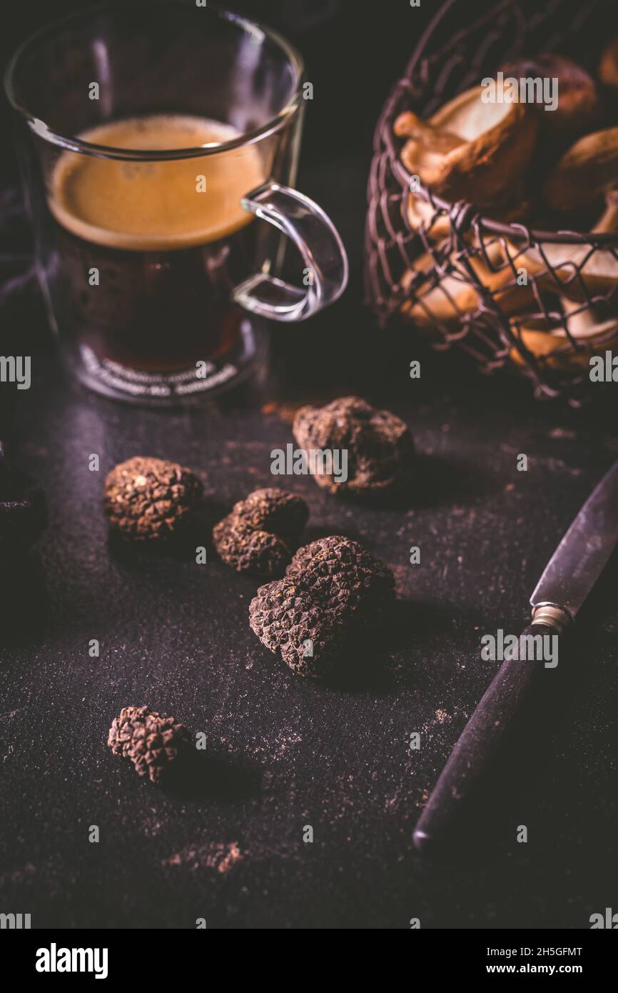 Black truffle on dark kitchen table with black coffee and mushrooms, cooking delicacy Stock Photo