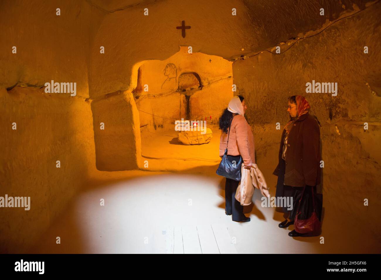 Two women visit an underground monastery. Stock Photo