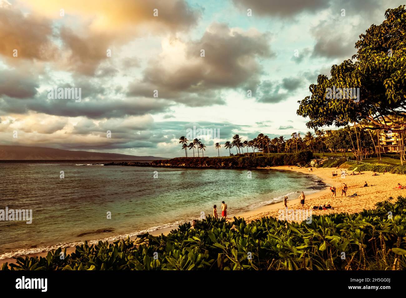Tourists enjoying Kapalua Beach on Kapalua Bay at sunset; Kapalua, Maui, Hawaii, United States