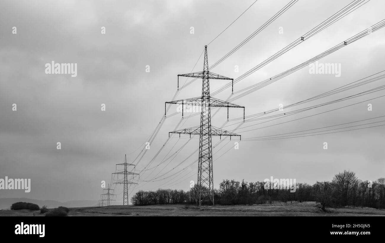 Grayscale shot of transmission towers against a cloudy sky Stock Photo ...